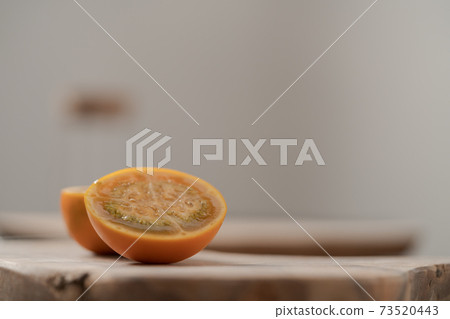 Lulo fruit sliced in halves on olive wood board on kitchen countertop 73520443