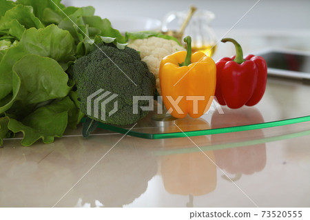 Kitchen interiors. Many vegetables and other meal at glass table are ready for been cooked soon Kitchen interiors. Many vegetables and other meal at glass table are ready for been cooked soon 73520555
