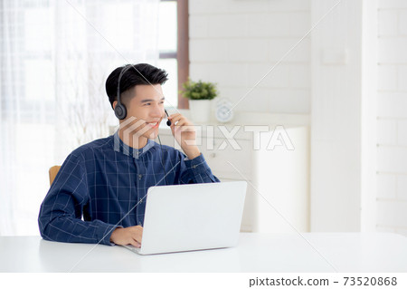 Young asian businessman working on laptop computer wearing headphone at home. Young asian businessman working on laptop computer wearing headphone at home. 73520868