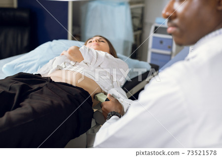 Extracorporeal shockwave therapy in urology. Cropped shot of lying woman patient, having ultrasound diagnostics to determine kidney stones position before the lithotripsy procedure. Extracorporeal shockwave therapy in urology. Cropped shot of lying woman patient, having ultrasound diagnostics to determine kidney stones position before the lithotripsy procedure. 73521578