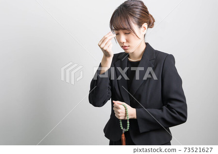 一個年輕女子在葬禮上燃燒的香火 73521627