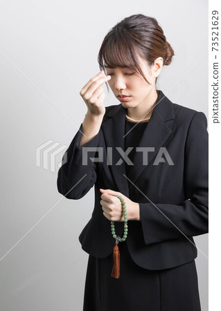 一個年輕女子在葬禮上燃燒的香火 73521629