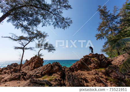 Photographer man standing on rock cliff have shooting session wild sea landscape Photographer man standing on rock cliff have shooting session wild sea landscape 73521951