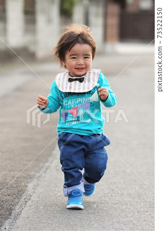 A 2-year-old boy walking while smiling 73522150