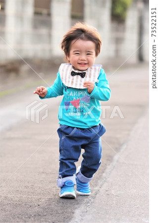 A 2-year-old boy walking while smiling 73522151