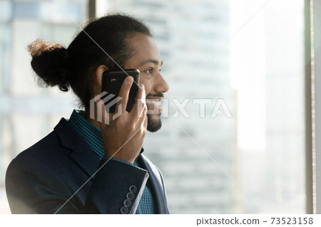 Smiling ethnic businessman use loudspeaker on modern cell 73523158