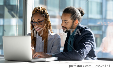 Diverse businesspeople work on laptop discuss project together Diverse businesspeople work on laptop discuss project together 73523161