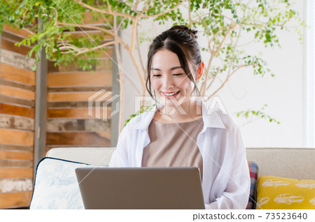 Young woman sitting on the couch and teleworking Young woman sitting on the couch and teleworking 73523640