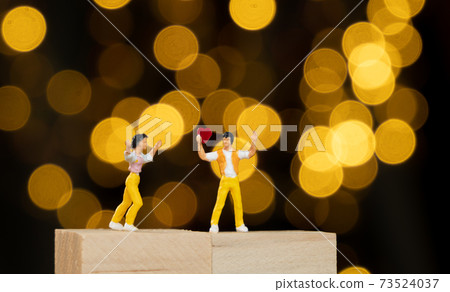 Miniature people man stand on wood cubic holding red heart for lover with yellow light bokeh background,Valentines concept Miniature people man stand on wood cubic holding red heart for lover with yellow light bokeh background,Valentines concept 73524037