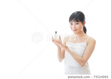 Young woman using perfume 73524093