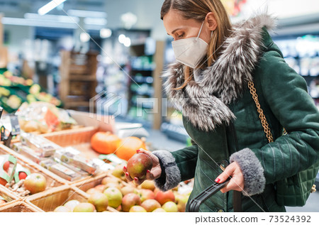 Woman wearing ffp2 face mask shopping in supermarket 73524392