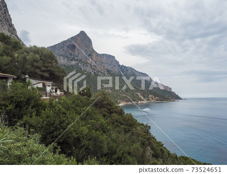 View over Gulf of Orosei from Pedra longa with limestone cliffs, green bushes, restaurante house and turquoise blue water. Famous travel touristic destination in Sardinia island, Italy. View over Gulf of Orosei from Pedra longa with limestone cliffs, green bushes, restaurante house and turquoise blue water. Famous travel touristic destination in Sardinia island, Italy. 73524651