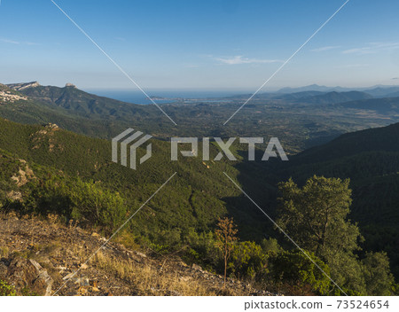 Aerial View of green landscape of Supramonte Mountains with Baunei and Arbatax village, limestone rocks and mediterranean sea and lush vegetation. Ogliastra, Sardinia, Italy. Summer blue sky Aerial View of green landscape of Supramonte Mountains with Baunei and Arbatax village, limestone rocks and mediterranean sea and lush vegetation. Ogliastra, Sardinia, Italy. Summer blue sky 73524654