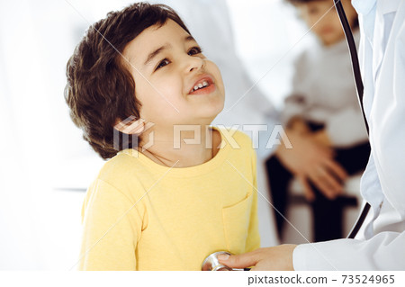 Woman-doctor examining a child patient by stethoscope. Cute arab boy at physician appointment. Medicine help concept Woman-doctor examining a child patient by stethoscope. Cute arab boy at physician appointment. Medicine help concept 73524965