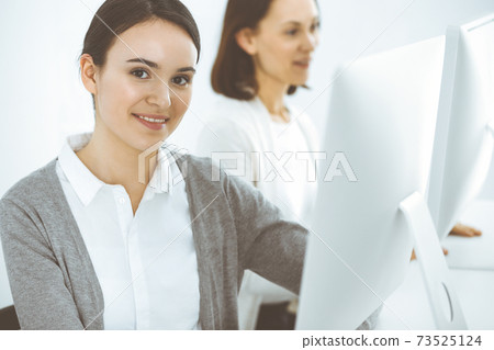 Business woman looking at camera at the background of working colleagues. Office life concept, headshot Business woman looking at camera at the background of working colleagues. Office life concept, headshot 73525124