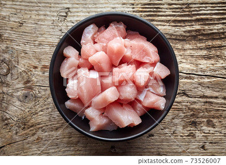 Raw cut meat chunks in black bowl, from above 73526007