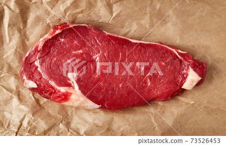 Raw beef steak on recycling paper, from above 73526453