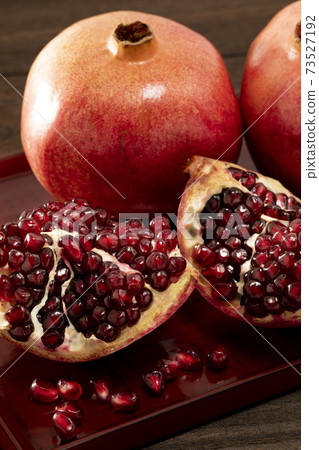 石榴放在深色木紋桌上 73527192