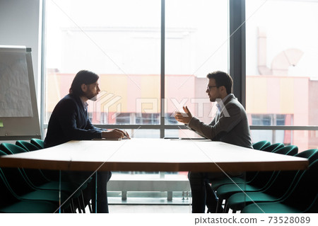 Focused confident young businessman making offer to partner. Focused confident young businessman making offer to partner. 73528089