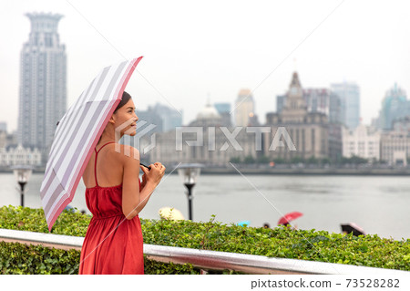 Rain umbrella Asian woman walking by Bund river Shanghai city enjoying walk on Asia China travel vacation. Rain umbrella Asian woman walking by Bund river Shanghai city enjoying walk on Asia China travel vacation. 73528282