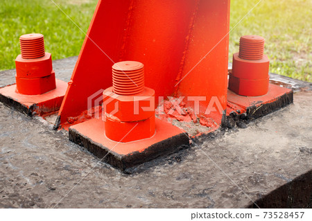 The red metal support is bolted to the concrete base with large bolts. Fixing a tower or tower to The red metal support is bolted to the concrete base with large bolts. Fixing a tower or tower to 73528457