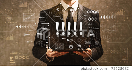 Exclamation marks with businessman holding a tablet computer 73528682