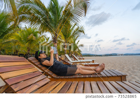 Asian woman relax on chair and use tablet 73528865