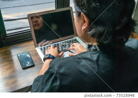 Rear view of Asian lesbian using laptop next to cellphone Rear view of Asian lesbian using laptop next to cellphone 73528946