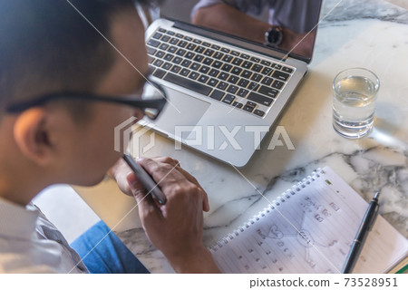 Young office man in glasses looking at mind mapping notebook Young office man in glasses looking at mind mapping notebook 73528951