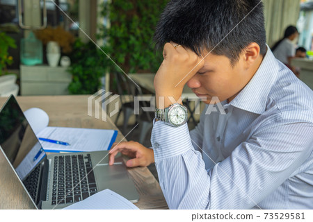 Tired businessman sitting with laptop and paperworks at workplace Tired businessman sitting with laptop and paperworks at workplace 73529581