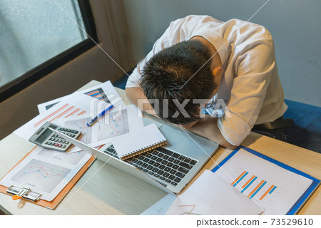 Stressed businessman fall asleep on messy office desk 73529610