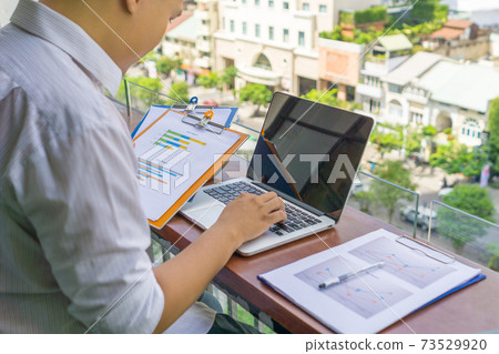 Asian man working on laptop and reading report Asian man working on laptop and reading report 73529920