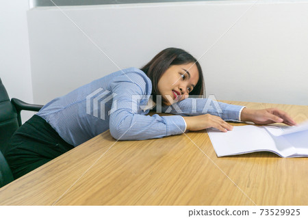 Tired office lady laid down on desk with paperwork in hand Tired office lady laid down on desk with paperwork in hand 73529925