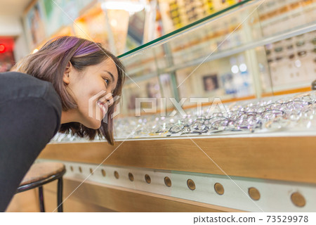 Smiling modern girl happy to buy pair of glasses Smiling modern girl happy to buy pair of glasses 73529978