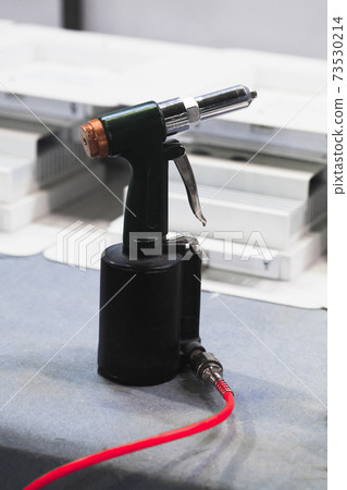 Black pneumatic rivet gun with red tubing 73530214