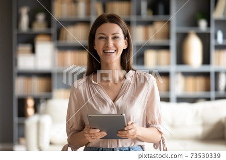 Head shot portrait smiling woman holding computer tablet in hands 73530339