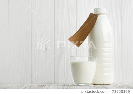 milk in glass and plastic bottle 73530369