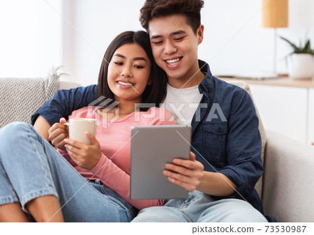 Asian Couple Using Tablet Computer Watching Movie Online At Home Asian Couple Using Tablet Computer Watching Movie Online At Home 73530987