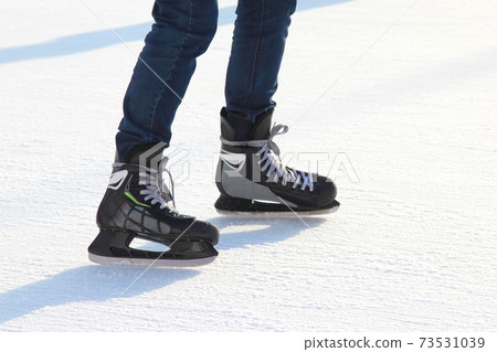 the legs of a man skating on the ice rink 73531039