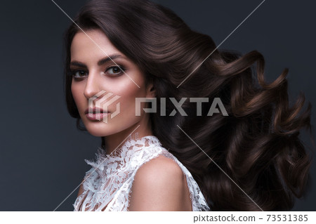 Beautiful brown-haired girl with a perfectly curls hair, and classic make-up. Beauty face and hair. 73531385