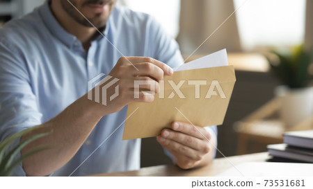Close up young man opening envelope with paper correspondence. Close up young man opening envelope with paper correspondence. 73531681