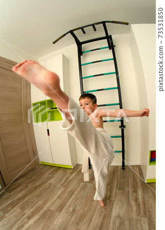 Little boy conducts karate training in kimono at home 73531850