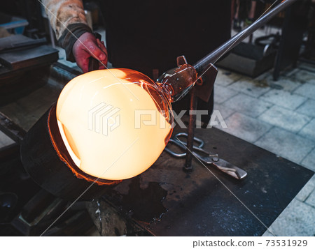 Glass blower forming hot piece of glass with wooden tool. Glass blower forming hot piece of glass with wooden tool. 73531929