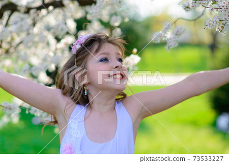Pretty little girl in blooming apple tree garden on beautiful spring day Pretty little girl in blooming apple tree garden on beautiful spring day 73533227