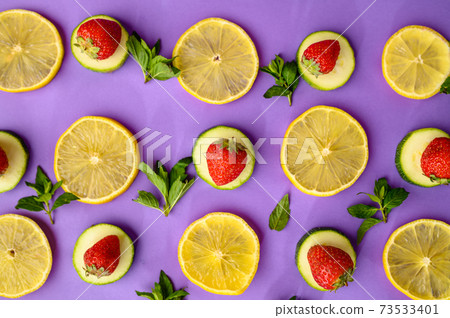 Lemon slices and strawberries on purple background 73533401