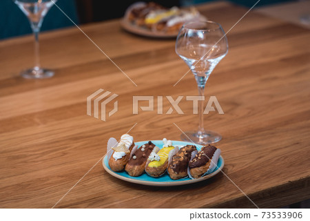 served table for food and vine tasting. Eclairs with different ganache and icing with different toppings 73533906
