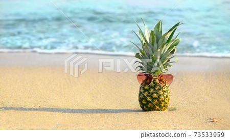 Fashion pineapple with heart shape glasses on a sandy beach 73533959