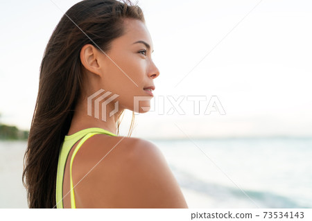 Beautiful young Asian woman relaxing by the beach. Wellness and healthy portrait of eurasian girl Beautiful young Asian woman relaxing by the beach. Wellness and healthy portrait of eurasian girl 73534143