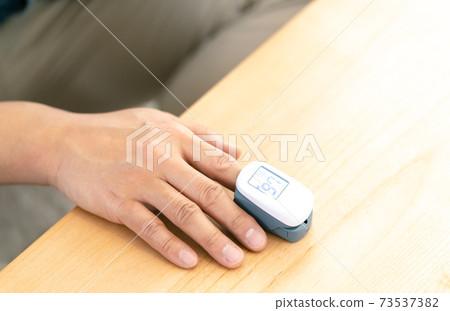 Men using a pulse oximeter Men using a pulse oximeter 73537382