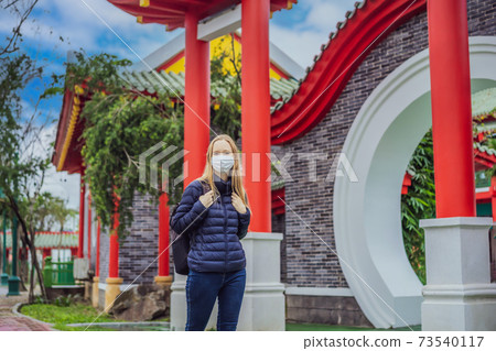 traveler in medical mask stopped on the street and looking at the Japanese, Chinese, Korean, Vietnamese traditional building. Tourists travel in Asia after the coronavirus epidemic traveler in medical mask stopped on the street and looking at the Japanese, Chinese, Korean, Vietnamese traditional building. Tourists travel in Asia after the coronavirus epidemic 73540117